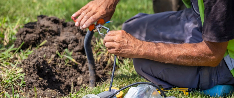 Technician repairing landscape lighting for a client in Waukee, IA.